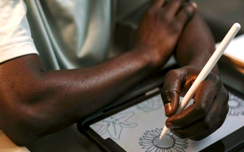 Person draws a sunflower on a tablet with a stylus, focusing on the digital illustration.